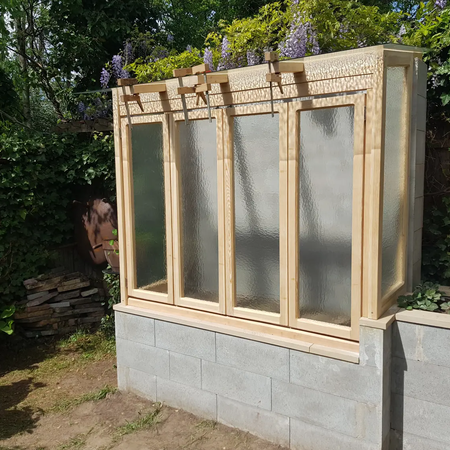 Ein Gewächshaus aus Holz mit Glasscheiben
