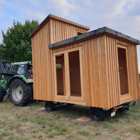 Eine Holzhütte wird mit einem Traktor verladen