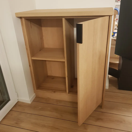 Eine Holzkommode mit Türe und zwei Fächern
